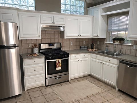 A kitchen with white cabinets and a stainless steel refrigerator.