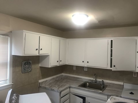 A kitchen with white cabinets and a marble countertop.