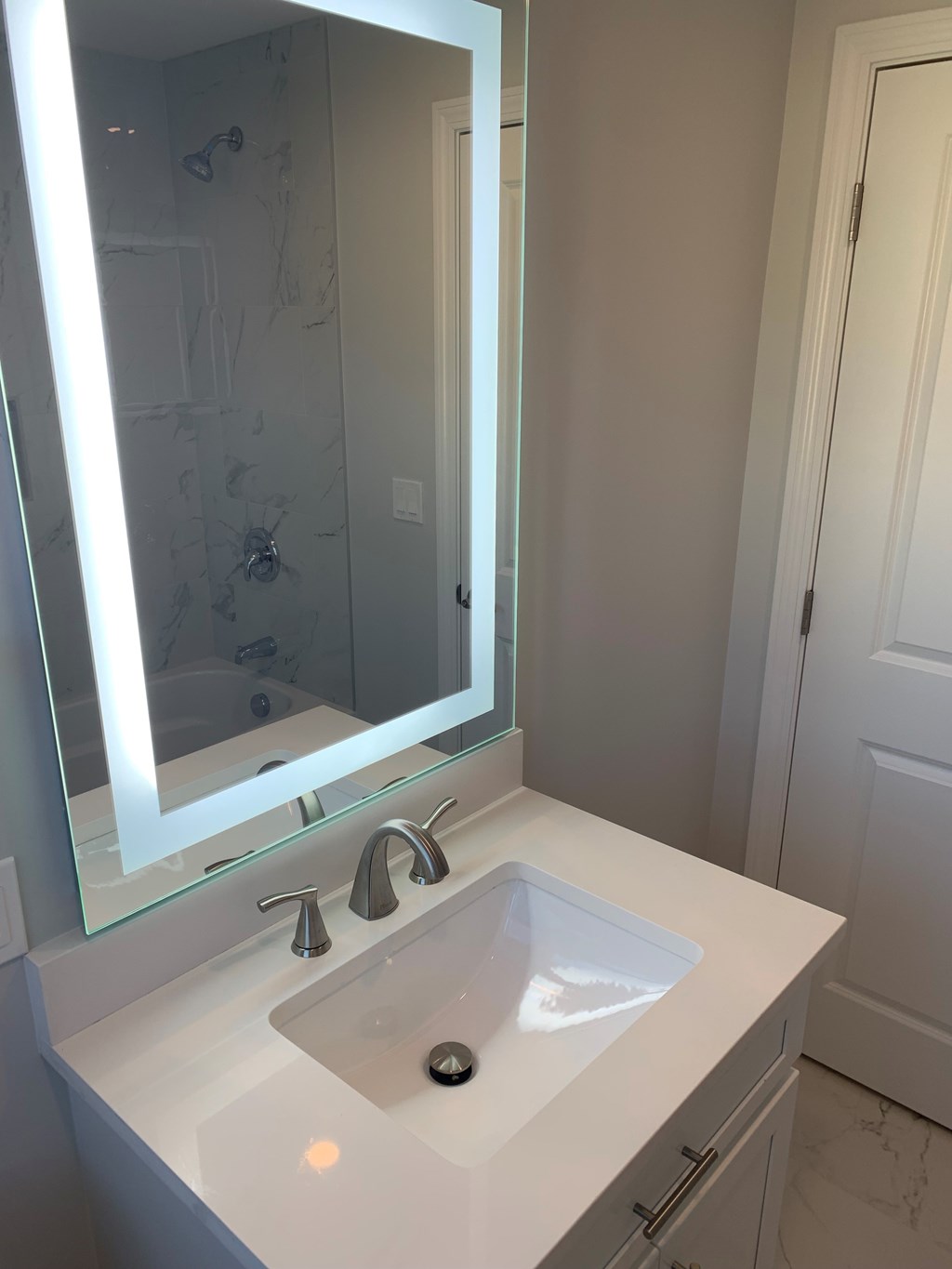 A white sink in a bathroom with a mirror above it.