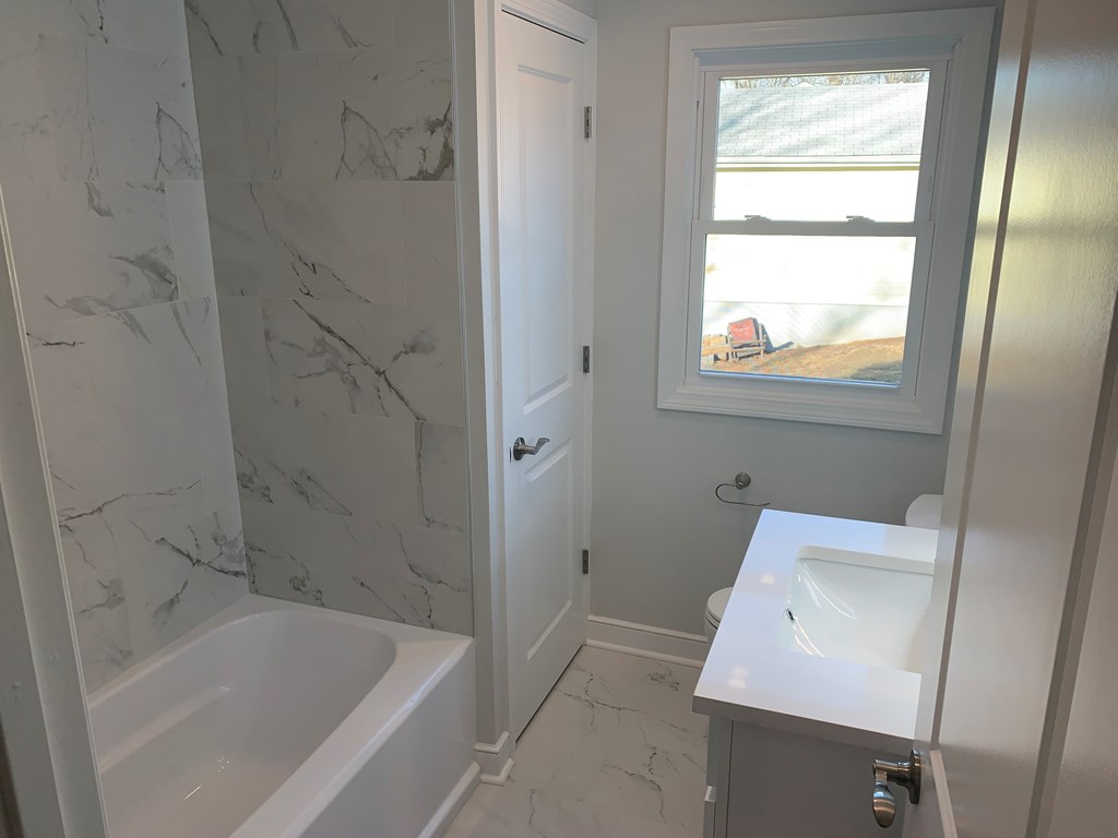 A bathroom with a marble wall and a window with a view of the beach.