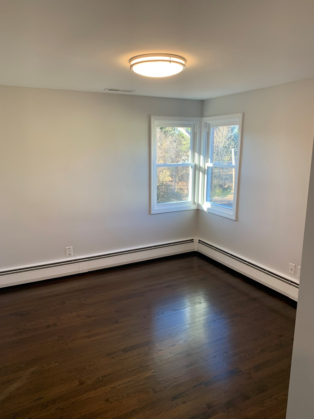 A room with a window and a wooden floor.