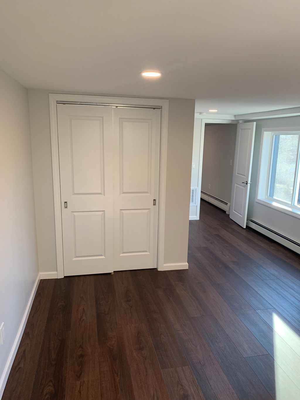 A room with a white door and brown flooring.