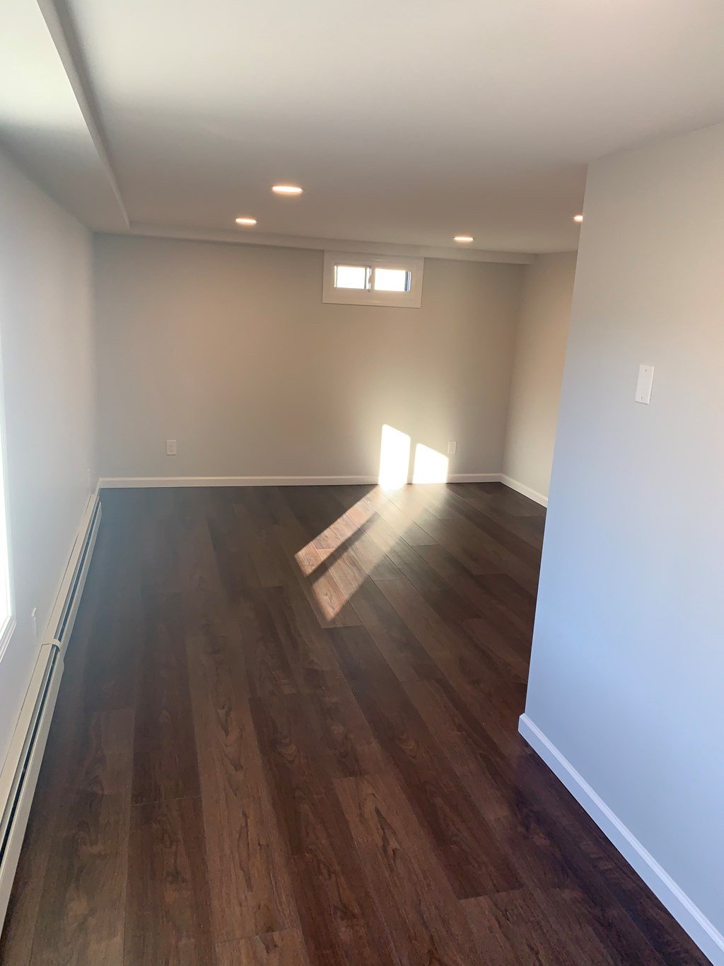 A room with wooden floors and a window letting in sunlight.