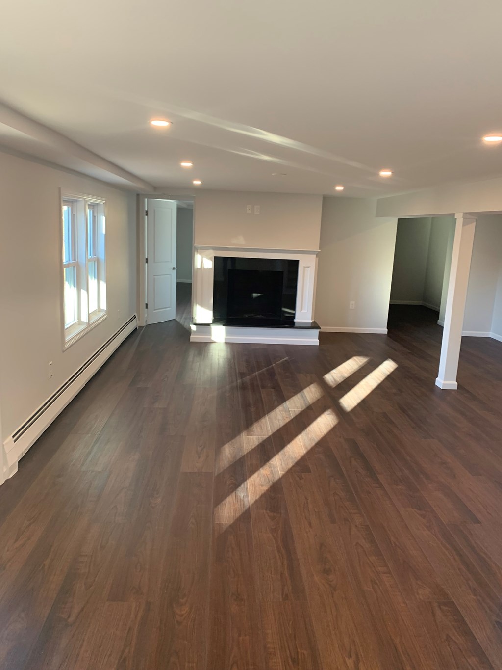 A large empty room with wooden floors and a fireplace.