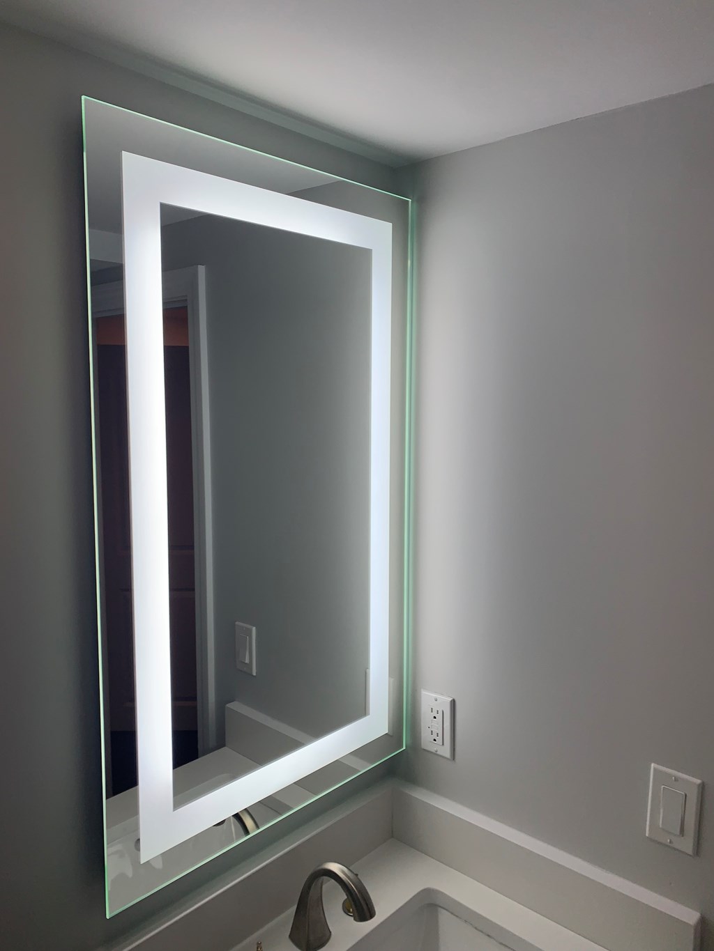 A bathroom with a large mirror above a sink.