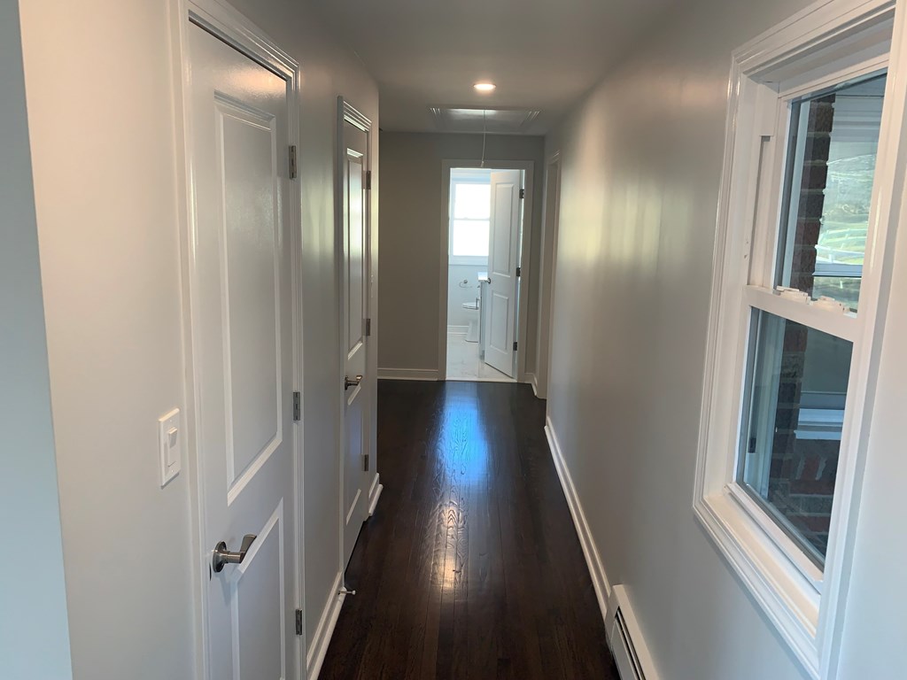 A long hallway with white doors and a window.