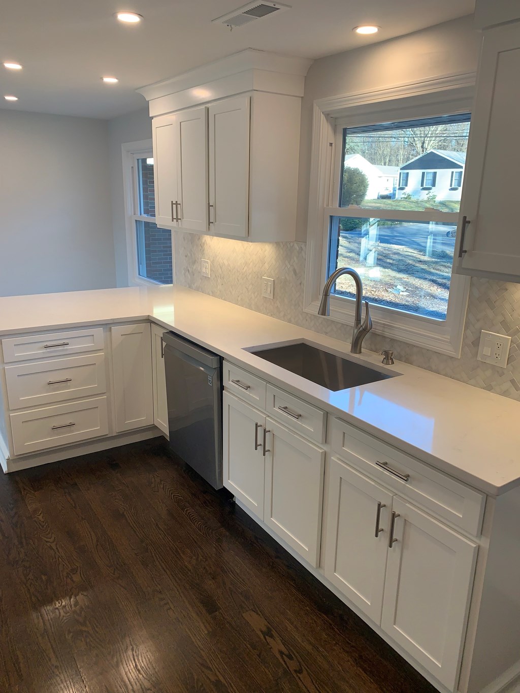 A kitchen with white cabinets and a window.