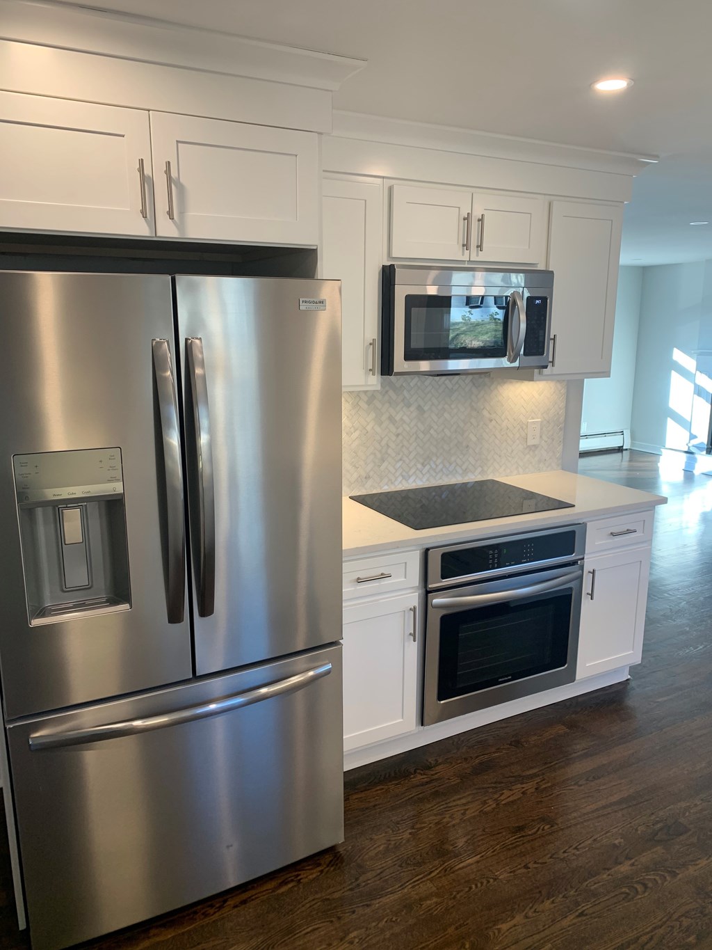 A modern kitchen with a stainless steel refrigerator and white cabinets.