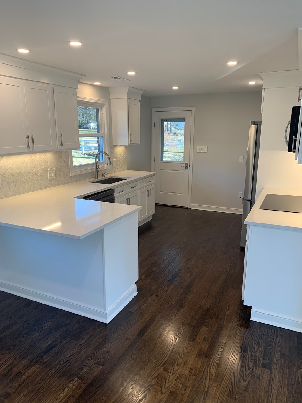 A kitchen with white cabinets and a white island.