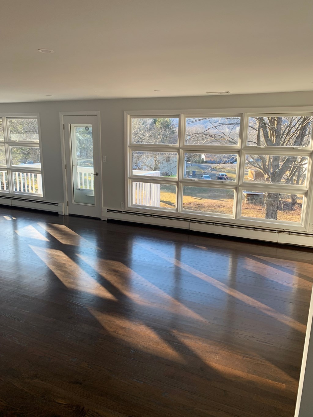 A room with wooden floors and large windows letting in natural light.