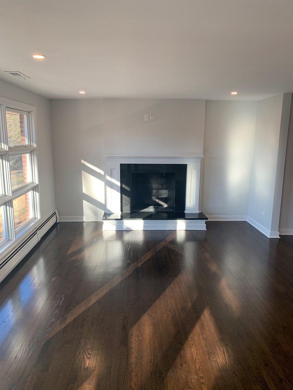 A room with a fireplace and wood flooring.