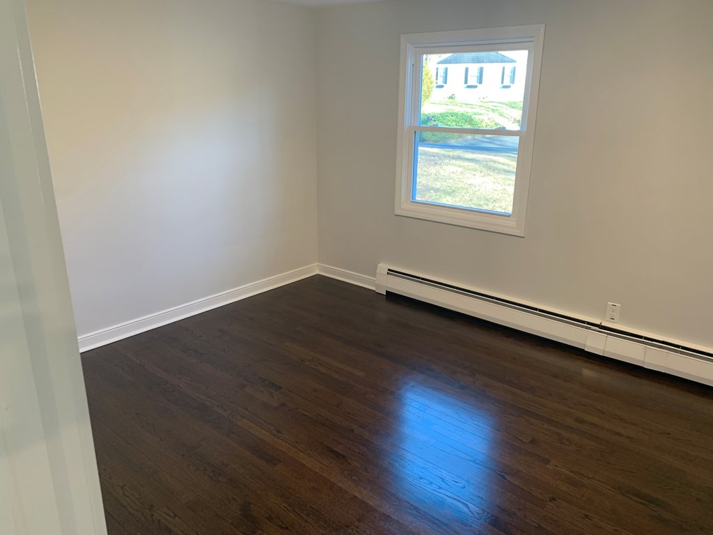 A room with a window showing a blue house outside.