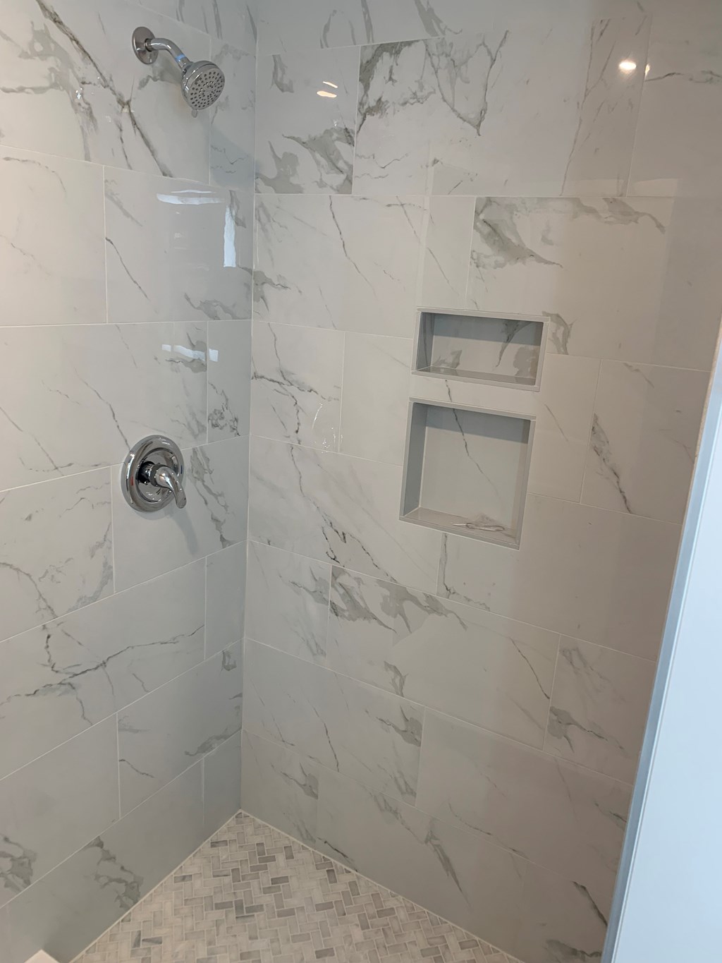 A shower area with a marble tile wall and floor.