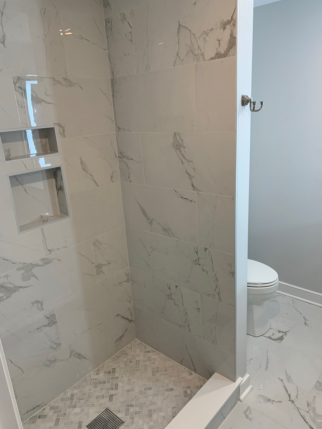 A white toilet is in a marble bathroom.