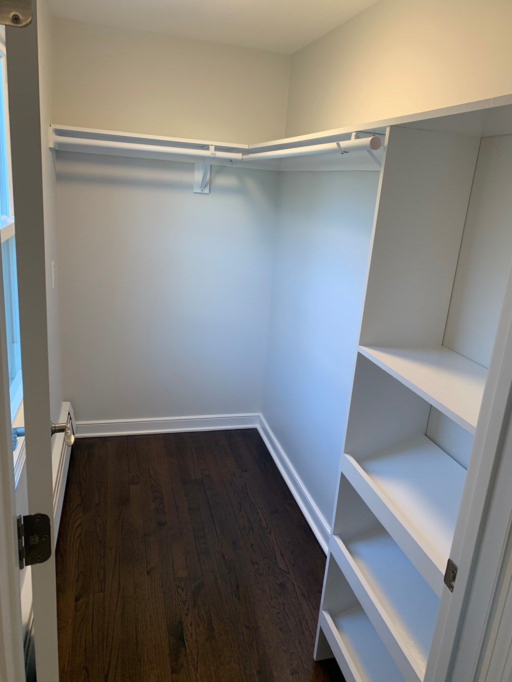 A white closet with shelves and a door.