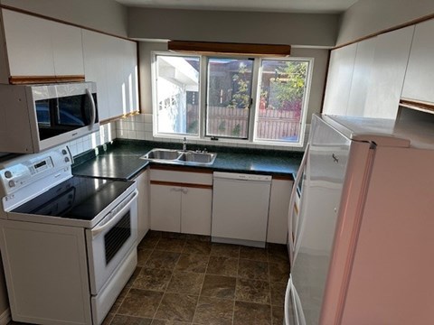 A kitchen with white cabinets and a black countertop.