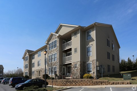 A large apartment building with a parking lot in front.