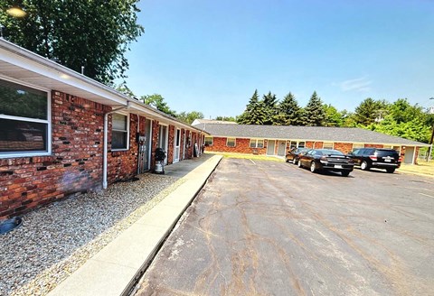 A parking lot with cars and a building with a brick wall.