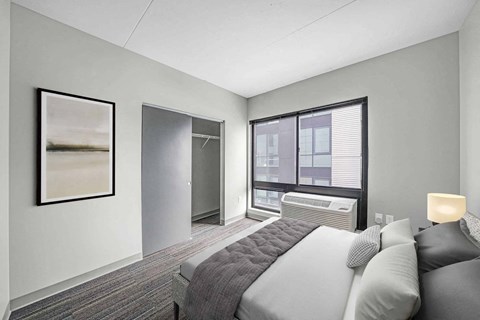 A bedroom with a bed, pillows, a window, and a painting on the wall.