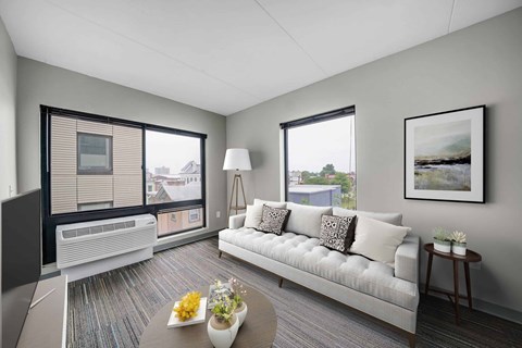 A living room with a couch, a coffee table, and a painting on the wall.