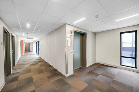 A hallway with a tiled floor and a window on the right side.