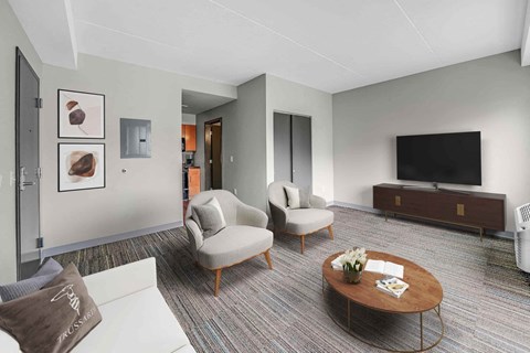 A living room with a white couch, a brown chair, a brown coffee table, and a flat screen TV.