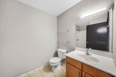 A bathroom with a toilet, sink, and mirror.