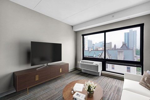 A modern living room with a flat screen TV and a view of the city.