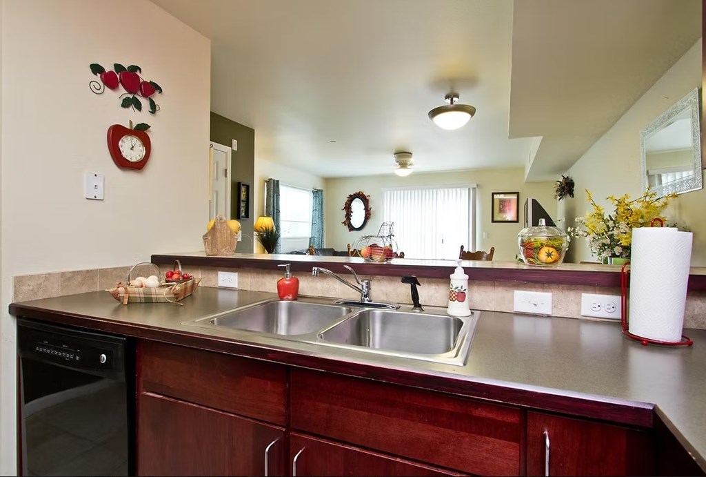 A kitchen with a stainless steel sink and wooden cabinets.