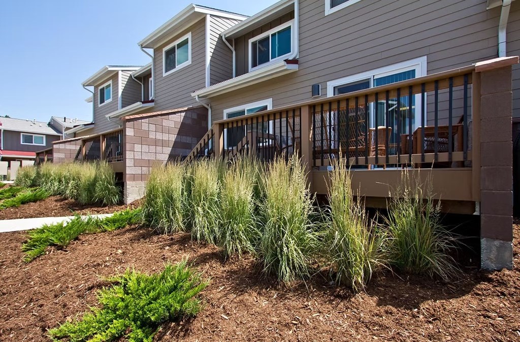 A row of houses with a brown fence and grass in the front.