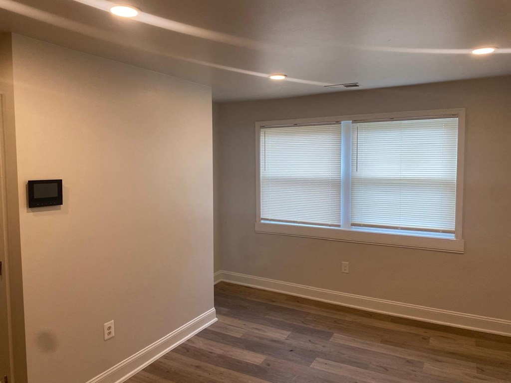 A room with a window covered by white blinds.