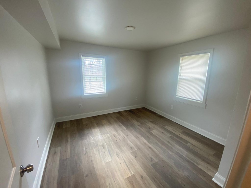 A room with wooden floors and two windows.