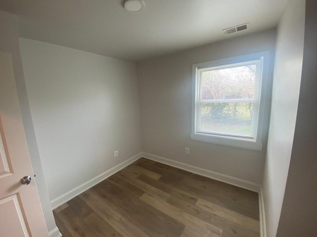 A room with a window and wooden flooring.