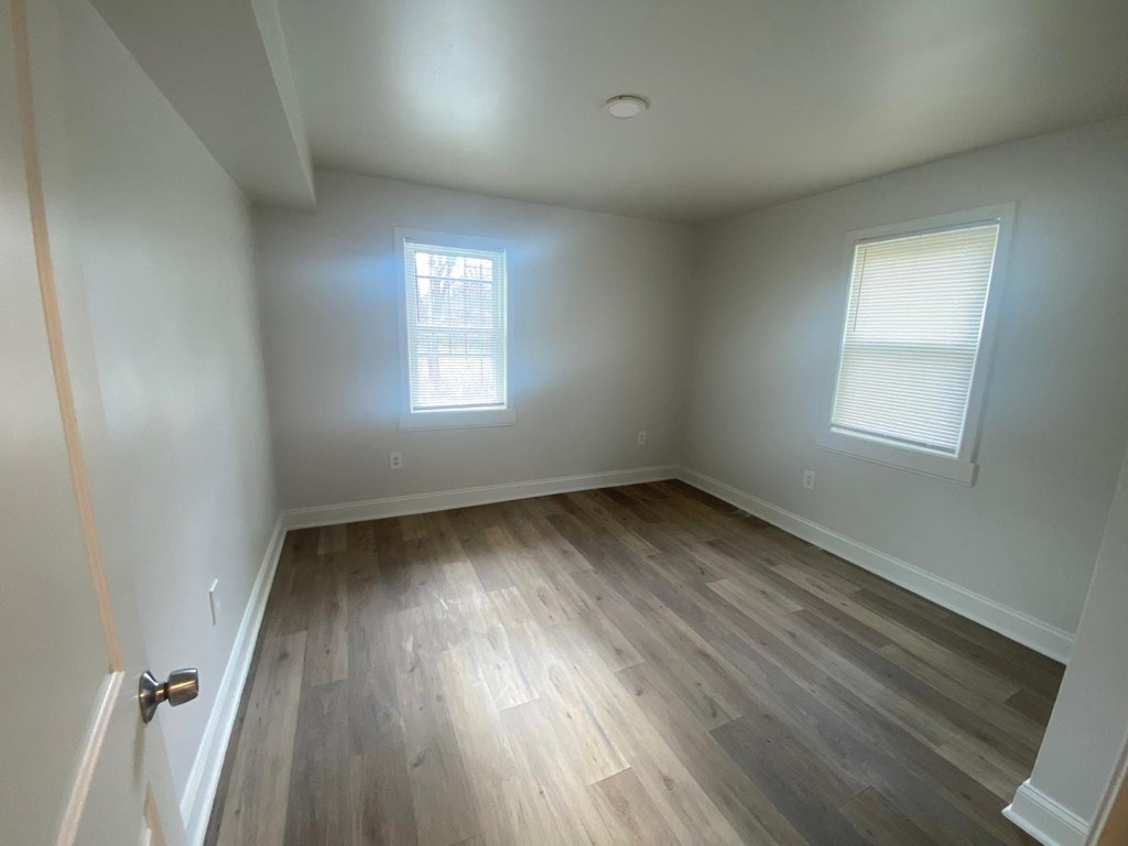 A room with wooden floors and two windows.