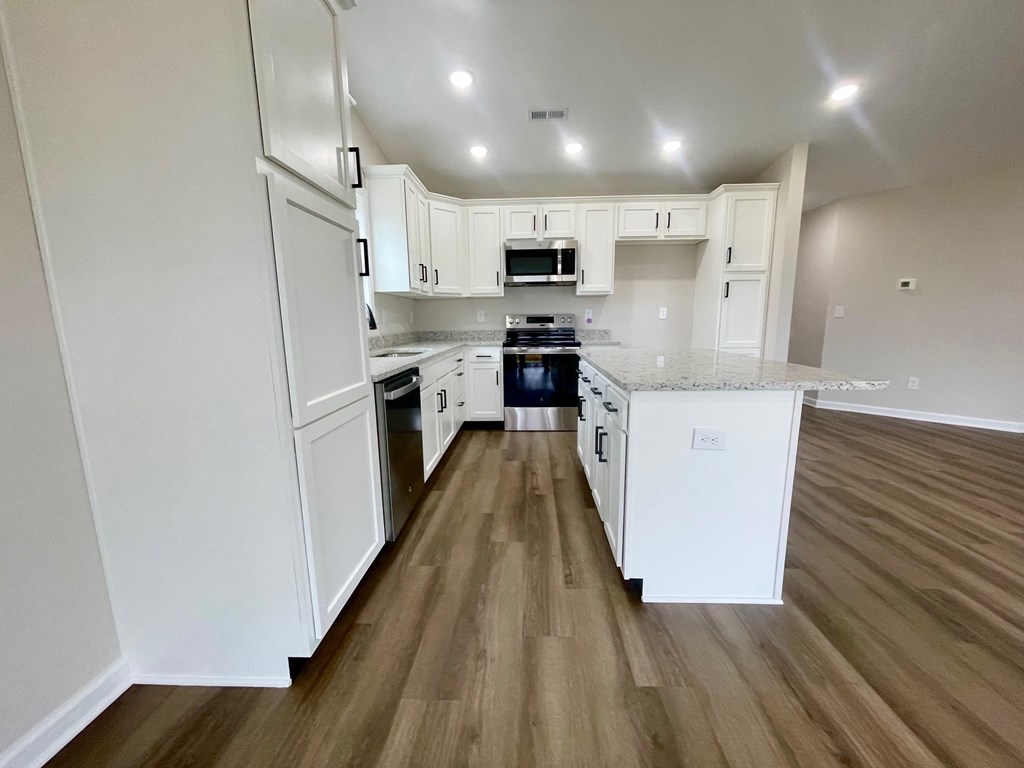 A kitchen with white cabinets and a wooden floor.