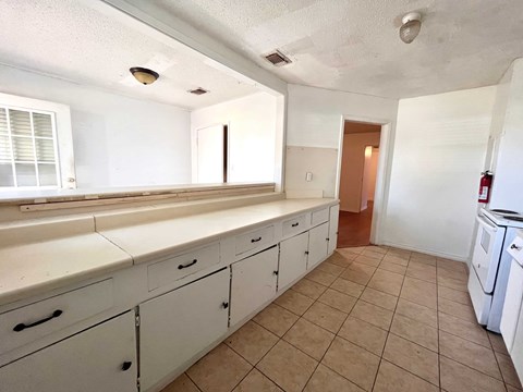 A kitchen with white cabinets and a tiled floor.