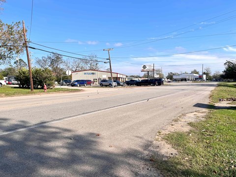 A street view with a building on the right and cars parked on the side of the road.