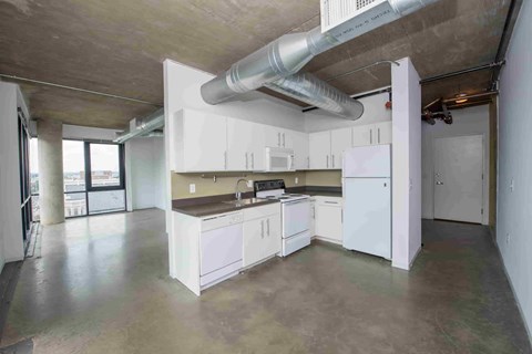 A kitchen with white cabinets and appliances in a large open space.