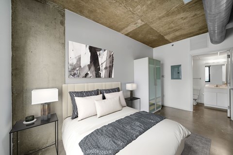 A bedroom with a large bed and a painting on the wall.
