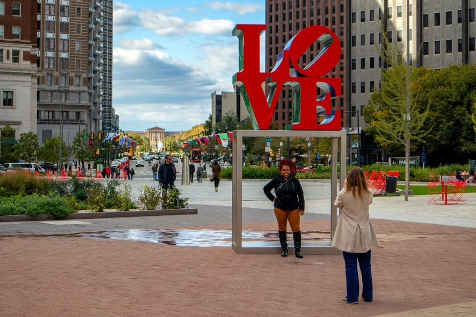 Two women stand in front of a large LOVE sign.