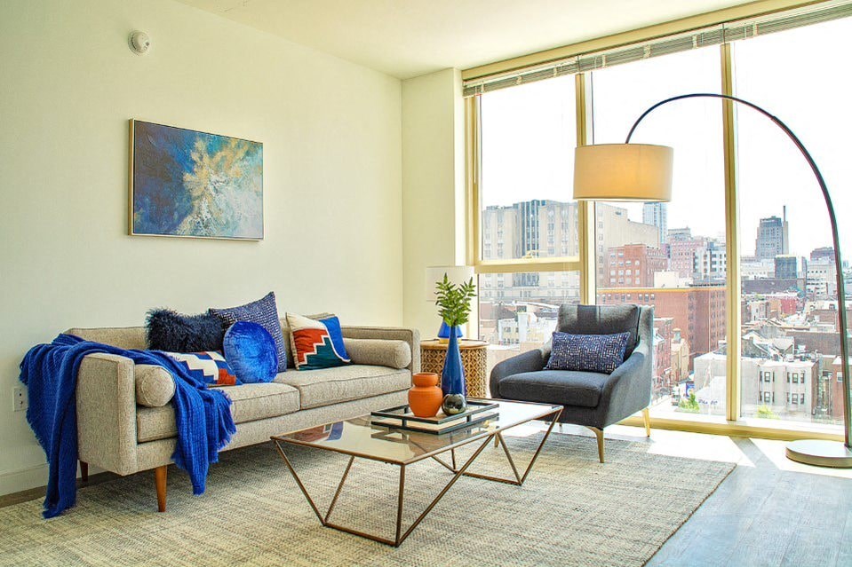 A living room with a couch, chair, and a large window overlooking a city.