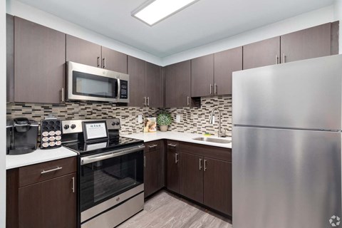 A kitchen with brown cabinets and a stainless steel refrigerator.