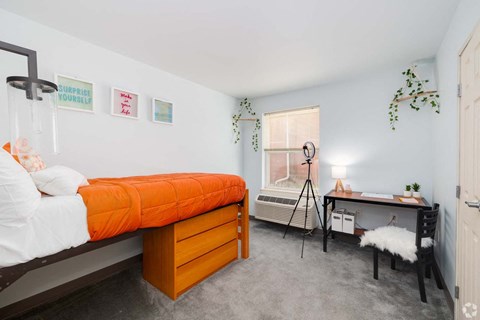 A bedroom with a bed, desk, and chair.