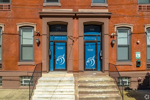 A red brick building with two blue doors and windows on the side.
