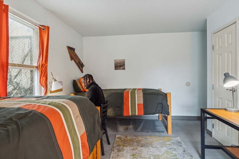 A person is sitting on a bed with a striped blanket.