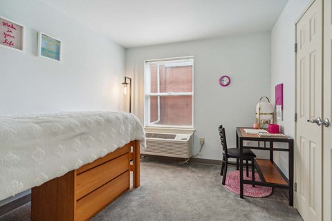 A bedroom with a bed, desk, and chair.