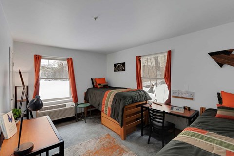 A bedroom with two beds, a desk, and a chair.