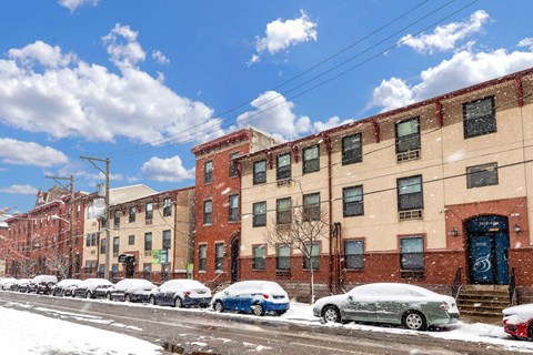 A row of buildings with cars parked in front of them.