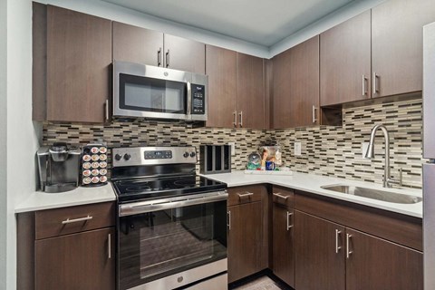 A kitchen with brown cabinets and a stone backsplash.