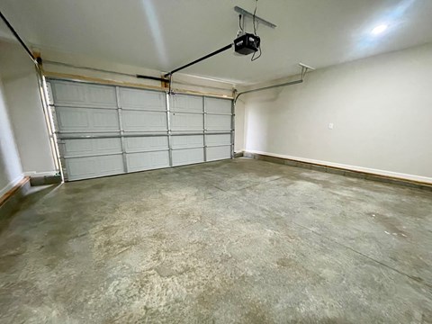 A spacious garage with a closed white door and a concrete floor.